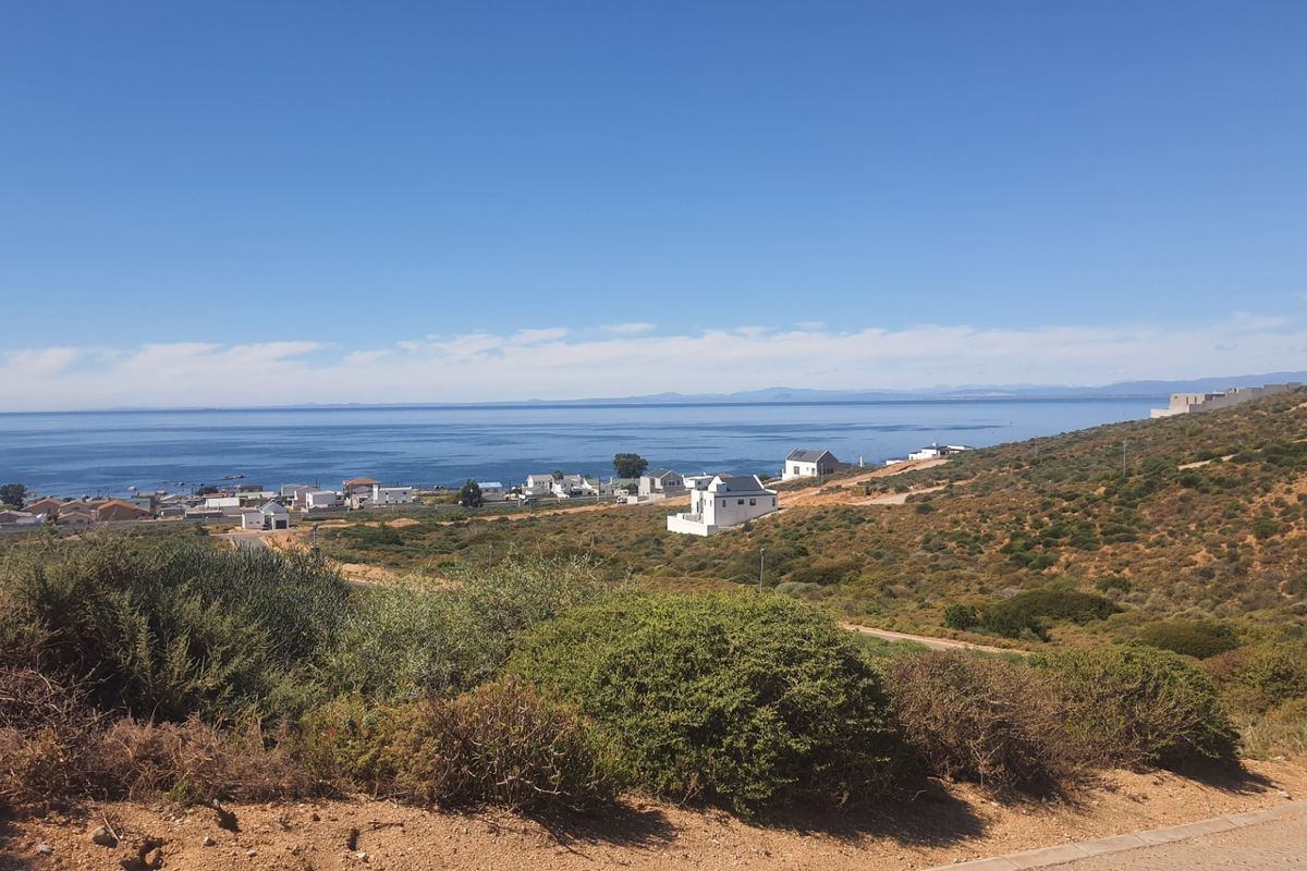 A scenic elevated view overlooking the coastline, surrounding residential properties, and the ocean, showcasing the natural landscape and coastal setting.