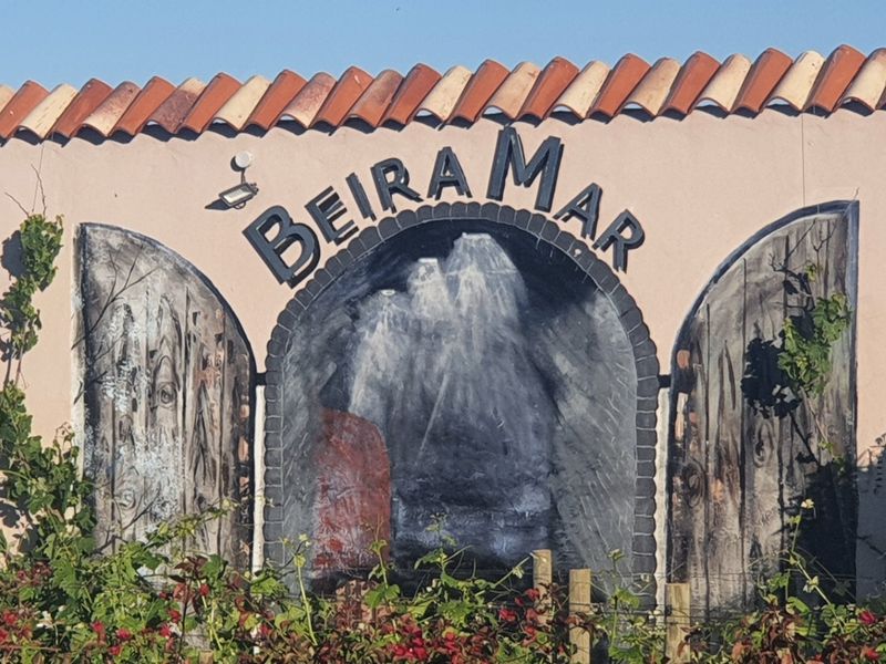 A view of the property boundary wall featuring a decorative mural and terracotta roof tiles.