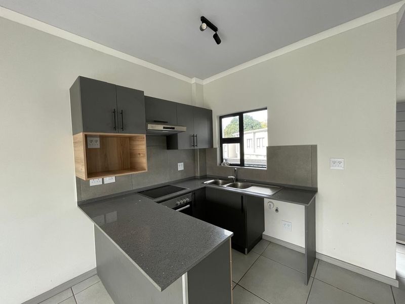 Modern kitchen featuring sleek grey cabinetry, stone countertops, integrated appliances, and a functional layout with a breakfast bar.