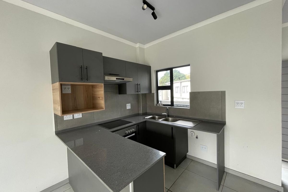 Modern kitchen featuring sleek grey cabinetry, stone countertops, integrated appliances, and a functional layout with a breakfast bar.