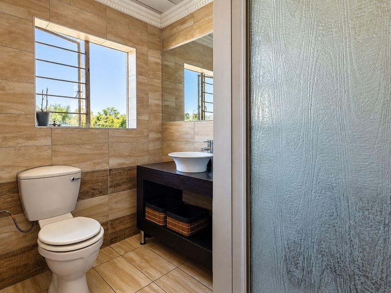 Modern bathroom featuring wood-look ceramic wall and floor tiles, a vessel sink vanity, and a frosted glass shower enclosure.