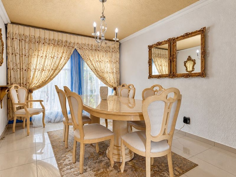 A formal dining room featuring tiled flooring, a textured ceiling with coving, and a central chandelier, providing a classic space for family meals.