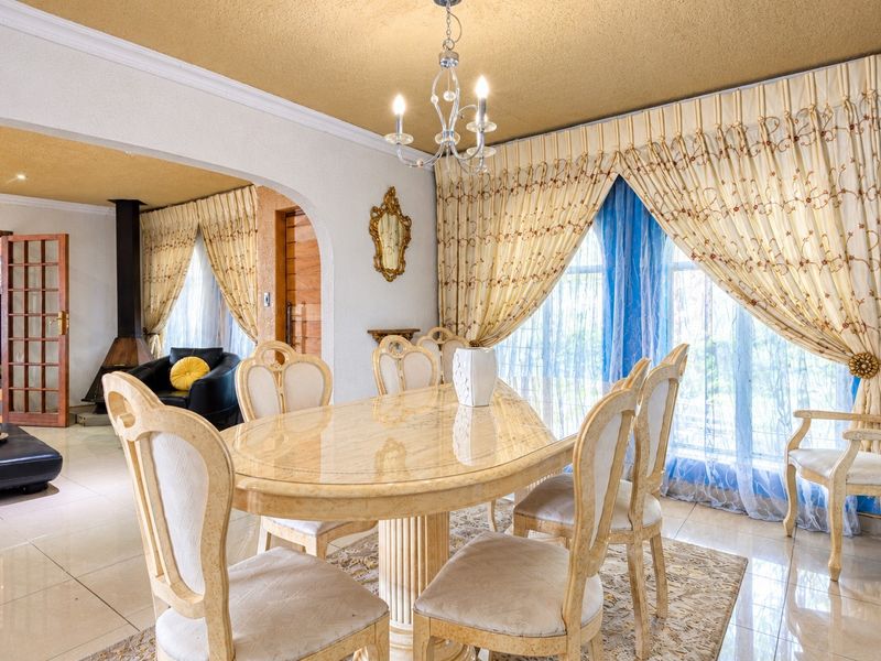 Spacious dining room featuring tiled flooring, a decorative chandelier, and an open-plan layout connecting to an adjacent living area with a fireplace.