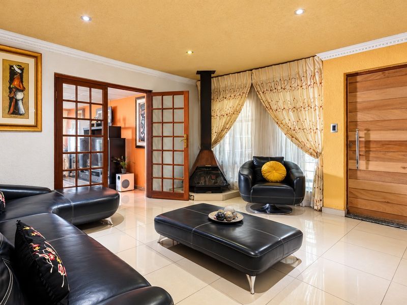 Spacious living room featuring tiled flooring, a modern freestanding fireplace, and elegant wooden french doors leading to an adjacent room.