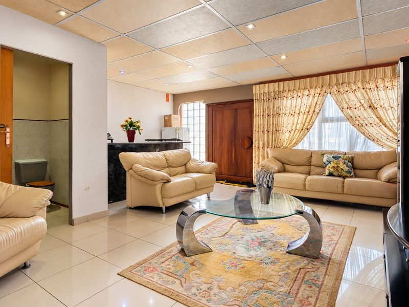 Open plan living area featuring tiled floors, a suspended ceiling with recessed lighting, and an integrated bar counter, with an adjacent small bathroom.