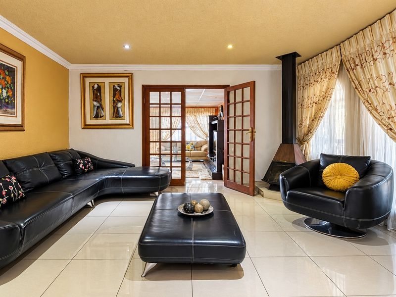 Spacious living room featuring polished tile flooring, a modern freestanding fireplace, and elegant french doors leading to an adjacent room.