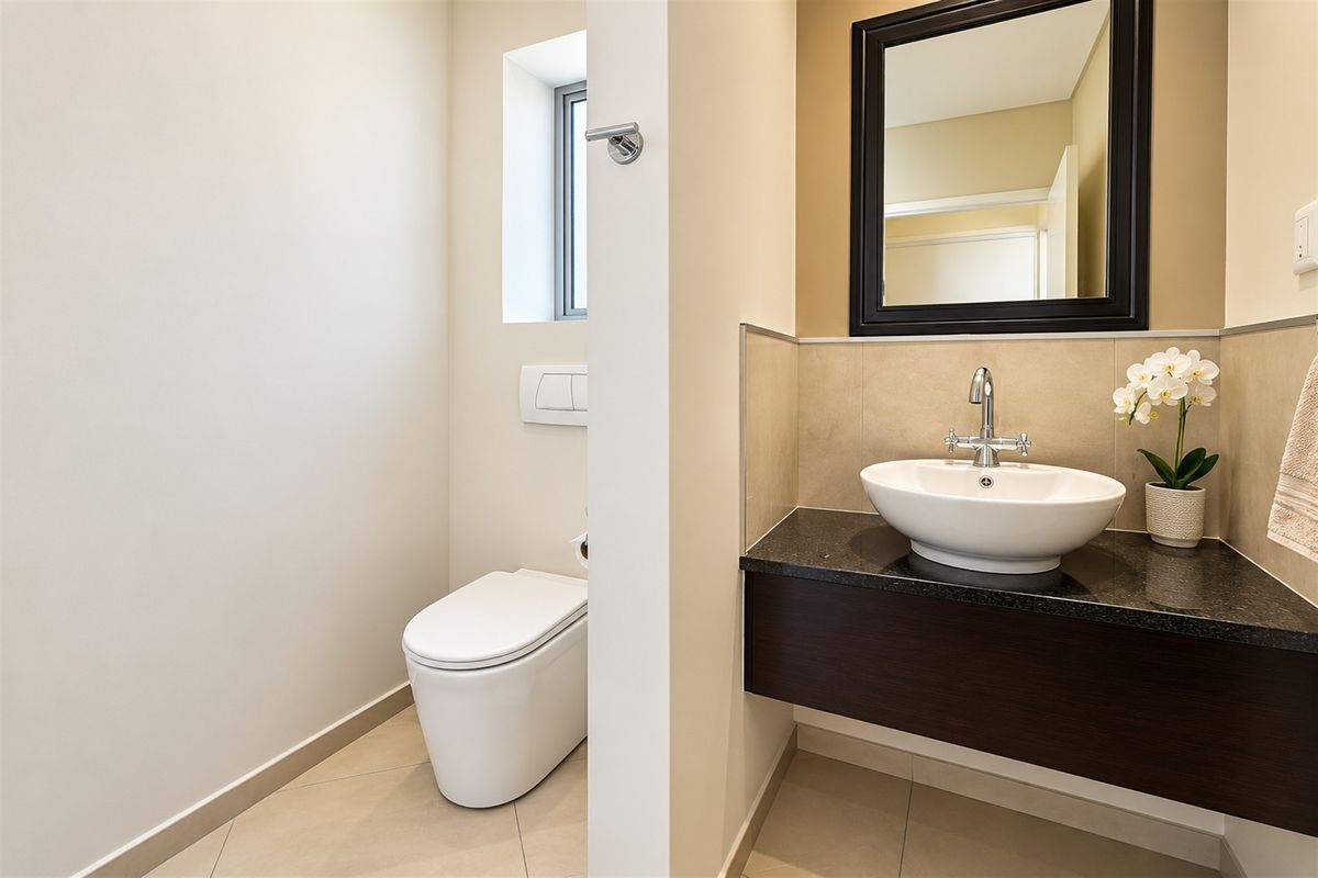 Modern bathroom featuring a wall-hung toilet with concealed cistern, a vessel sink on a granite vanity countertop, and a floating vanity cabinet.