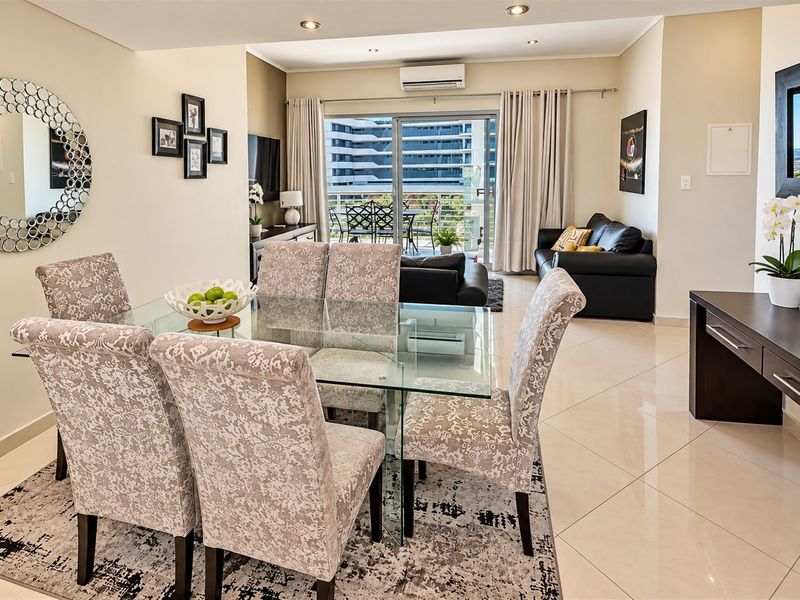 Spacious open-plan living and dining area featuring tiled flooring, recessed lighting, and direct access to a private balcony through sliding glass doors.