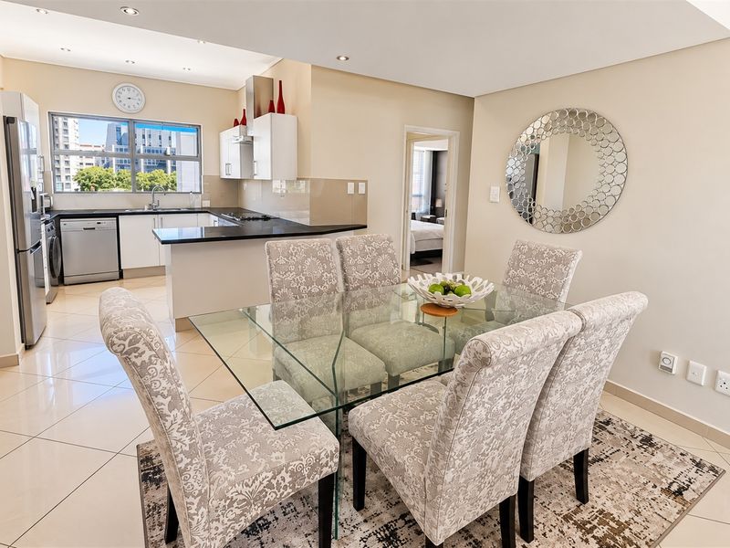 Open-plan living and dining area featuring a modern kitchen with granite countertops, tiled flooring, and recessed lighting, creating a bright and functional space.