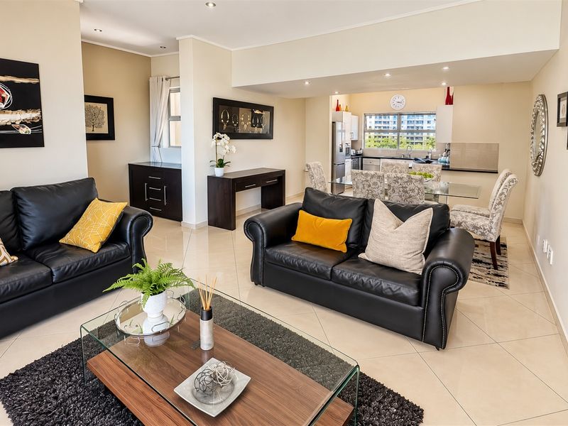 Spacious open-plan living and dining area featuring tiled floors, recessed lighting, and a functional kitchen with modern cabinetry and countertops.