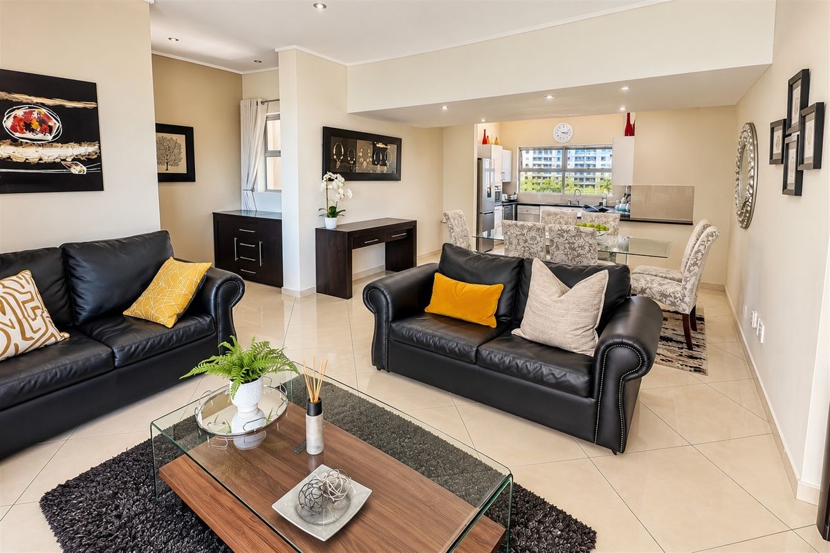 Spacious open-plan living and dining area featuring tiled floors, recessed lighting, and a functional kitchen with modern cabinetry and countertops.