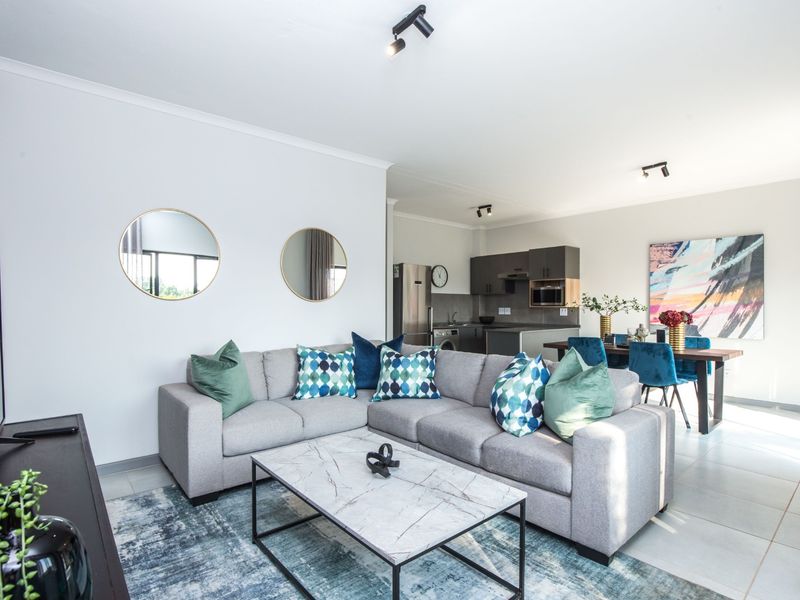 Modern open-plan living area featuring a contemporary kitchen with built-in cabinetry and tiled flooring, seamlessly flowing into the dining and lounge space.