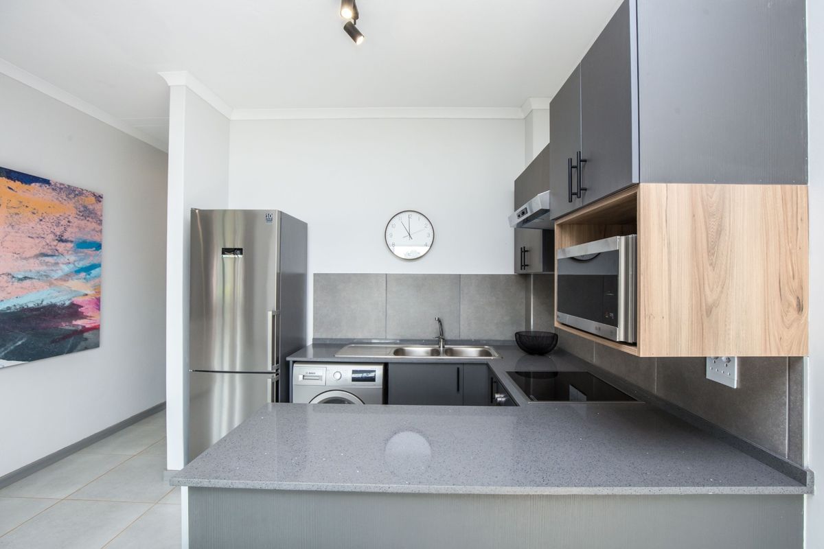 Modern kitchen featuring sleek grey cabinetry, stone countertops, integrated appliances, and a functional layout with a breakfast bar.
