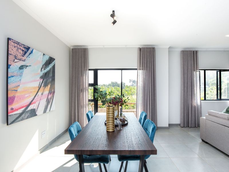 Bright and modern open-plan living and dining area featuring large windows, neutral tiled flooring, and contemporary lighting fixtures.