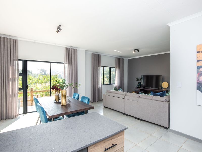 Spacious open-plan living and dining area featuring tiled floors, modern accent wall, and large sliding doors leading to an outdoor space.