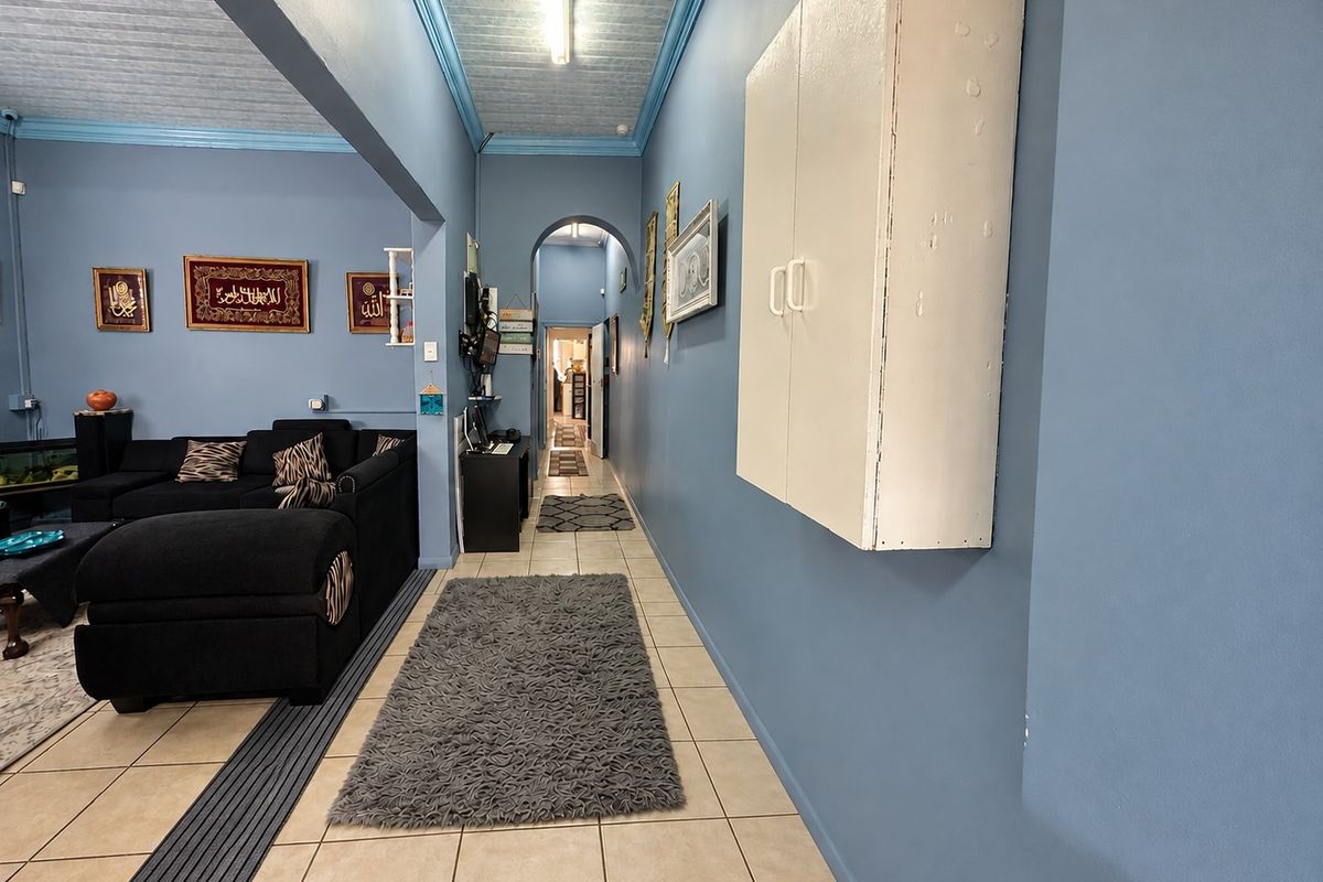 A living area featuring tiled flooring, a built-in wall cabinet, and an arched transition leading to a hallway.
