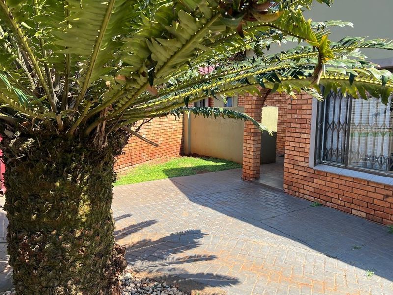 A private rear courtyard featuring brick walling, a paved patio area, and a covered archway entrance.