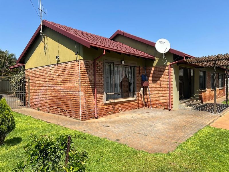Rear view of the house featuring a brick facade, tiled roof, paved patio area, and a timber pergola structure.