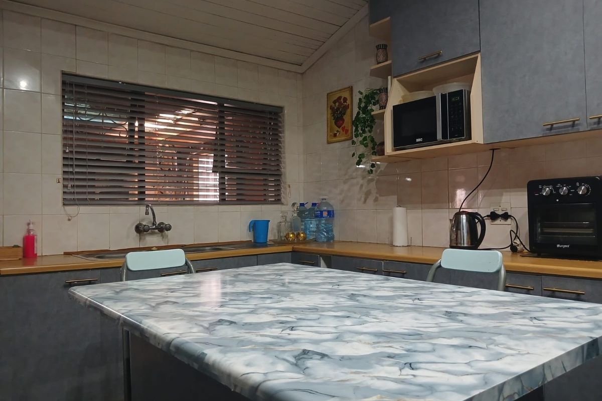 A functional kitchen featuring grey cabinetry, tiled backsplash, and a central island with a marble-effect countertop, providing ample workspace and storage.