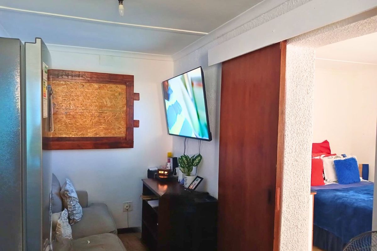 A compact living area featuring textured walls and a sliding door leading to an adjacent bedroom.