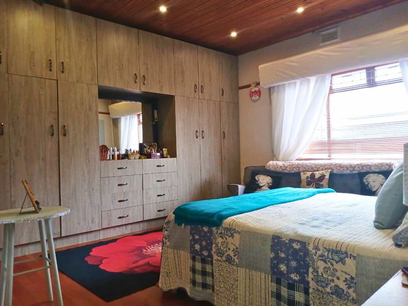 A bedroom featuring extensive built-in cabinetry, warm timber ceiling finishes, recessed lighting, and laminate flooring, offering ample storage space.