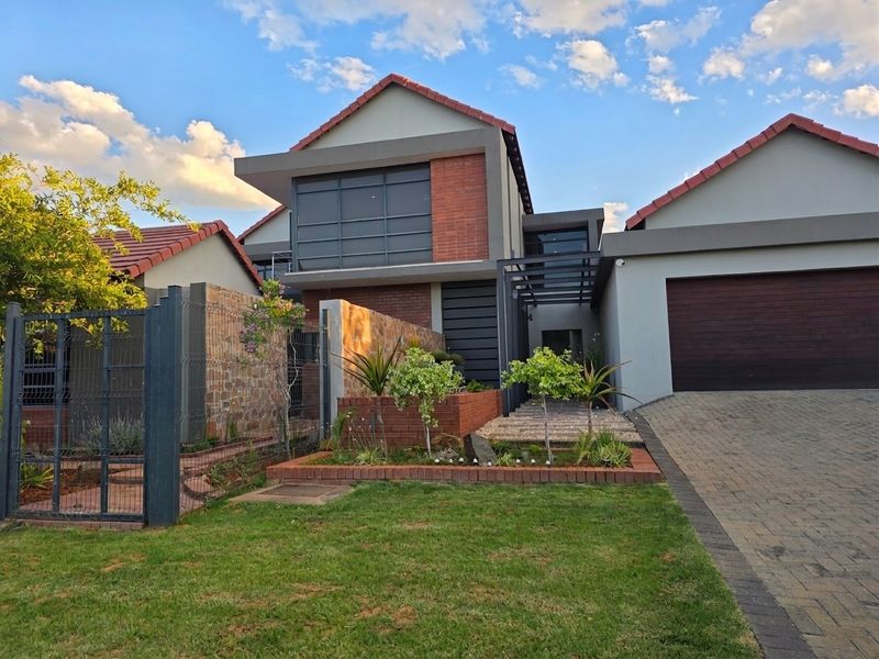 Modern double-storey residential home featuring a brick and plaster facade, tiled roof, paved driveway, and an integrated double garage.