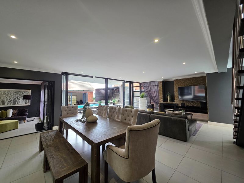 Spacious open-plan living and dining area featuring modern tiled floors, a stone feature wall with built-in fireplace, and seamless access to the outdoor pool area.