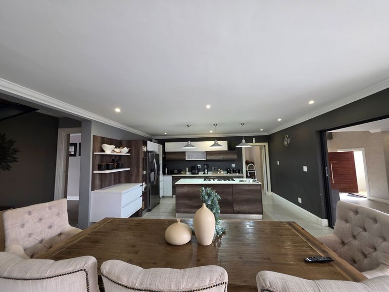 Spacious open-plan kitchen and dining area featuring a central island, modern cabinetry, recessed lighting, and neutral tiled flooring.