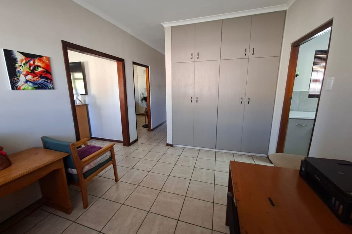 Bedroom featuring neutral tiled flooring and extensive built-in cupboards, providing ample storage space with access to adjacent rooms.