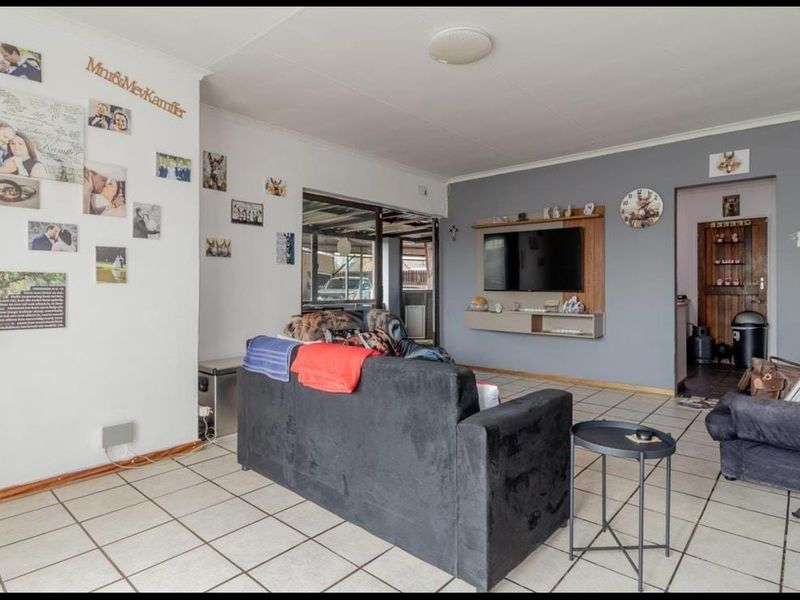 A living room featuring tiled flooring, a built-in media console, and a sliding glass door leading to an outdoor area.