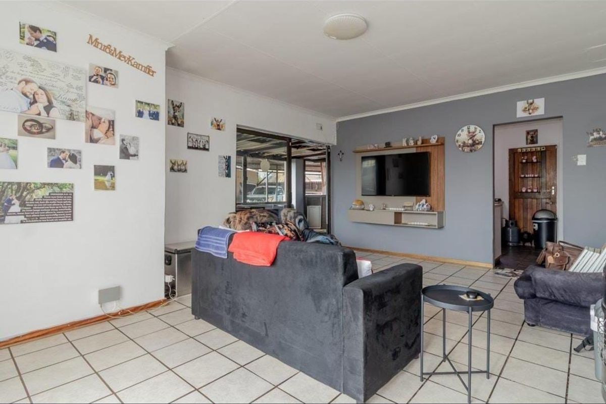 A living room featuring tiled flooring, a built-in media console, and a sliding glass door leading to an outdoor area.