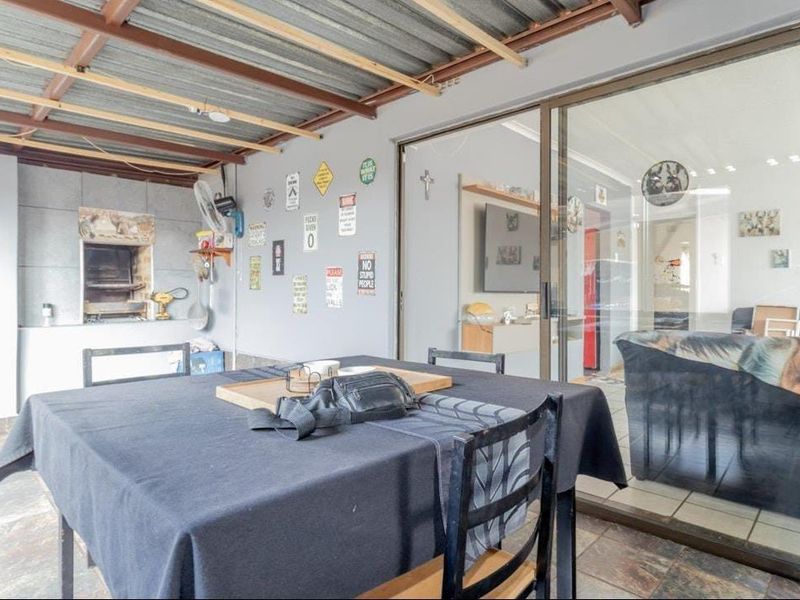 Covered patio area featuring a built-in braai, tiled flooring, and sliding glass doors providing access to the interior living space.