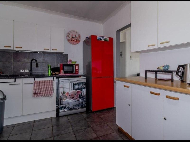 A functional kitchen featuring white cabinetry, dark tiled backsplash, laminate countertops, and tiled flooring.