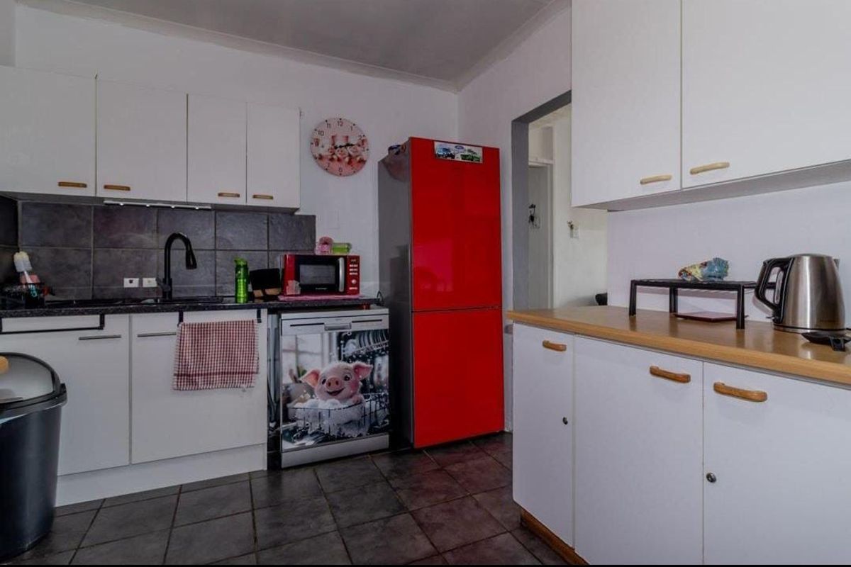A functional kitchen featuring white cabinetry, dark tiled backsplash, laminate countertops, and tiled flooring.