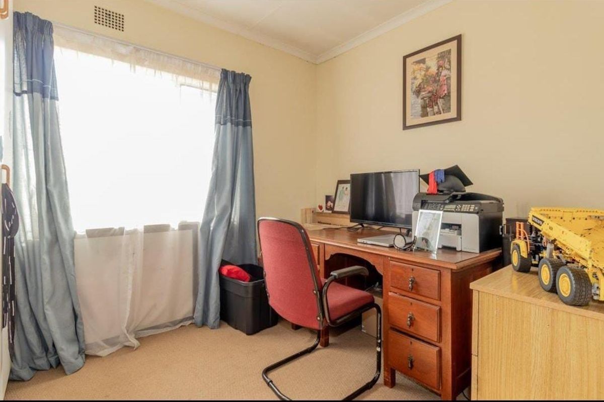 A functional bedroom featuring carpeted flooring and a window, suitable for use as a bedroom or home office space.