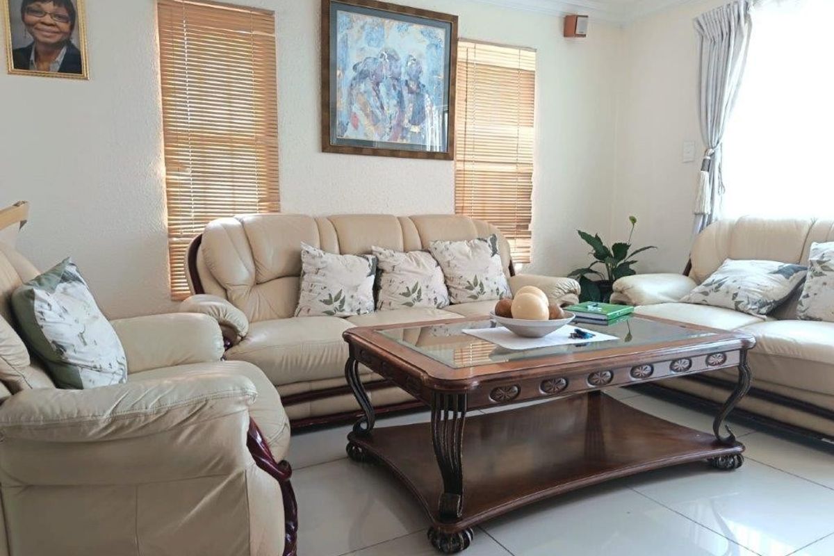 A bright and well-maintained living room featuring neutral tiled flooring, coved ceilings, and venetian blinds on the windows.