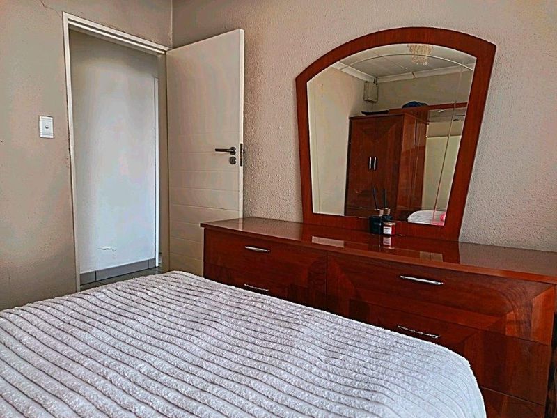 A bedroom interior featuring standard wall finishes and an internal door, showing signs of wear and tear on the wall surfaces.