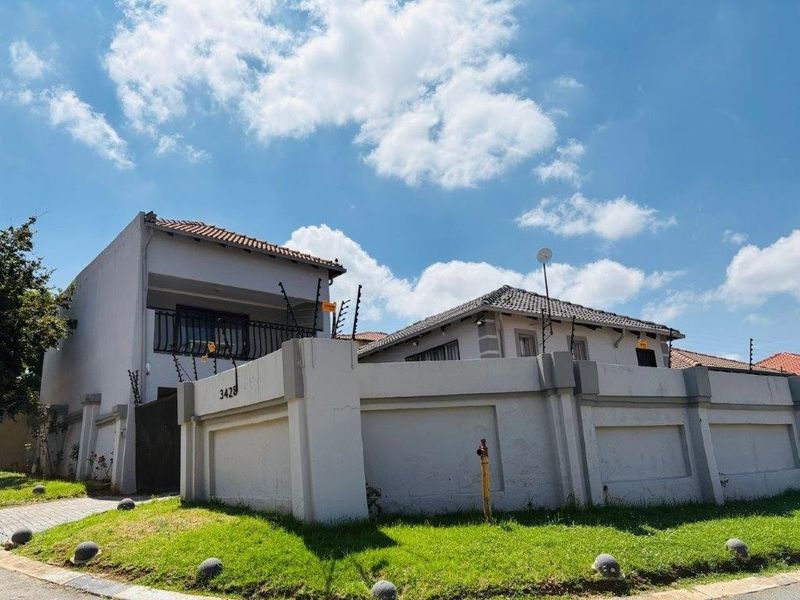 Front exterior view of a two-story residential property featuring a perimeter wall with electric fencing and a tiled roof.