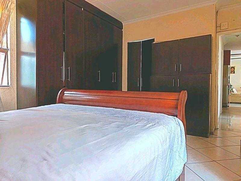 A bedroom featuring extensive dark wood built-in cupboards and tiled flooring, offering ample storage space within a functional layout.