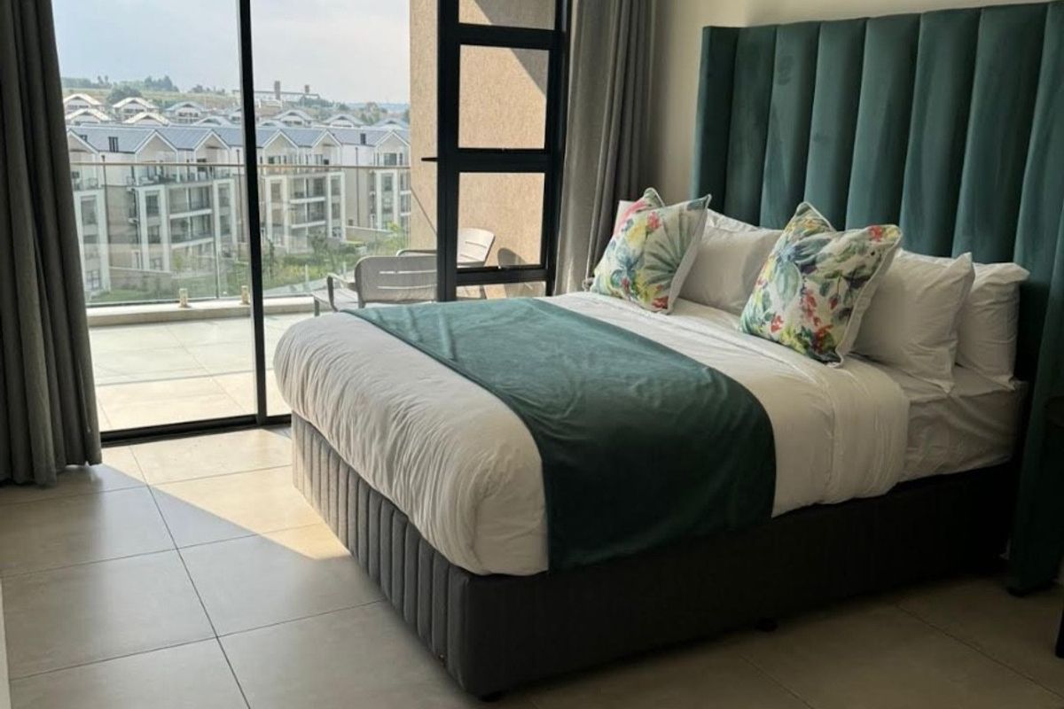 Modern bedroom featuring large format floor tiles and a large sliding glass door providing access to a private balcony with neighborhood views.