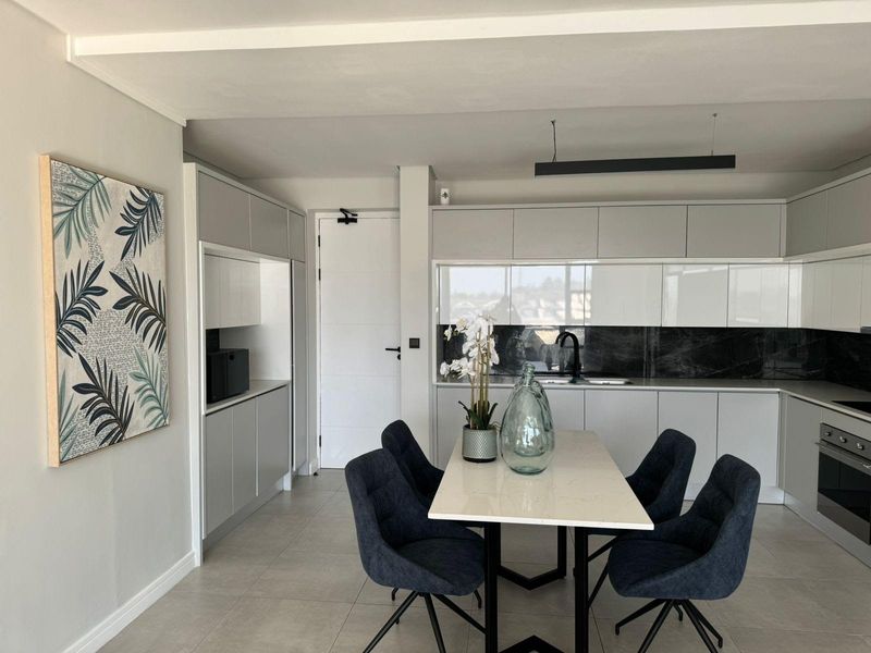 Modern kitchen featuring sleek handleless cabinetry, stone countertops, integrated oven, and high-quality finishes in a bright, open-plan layout.