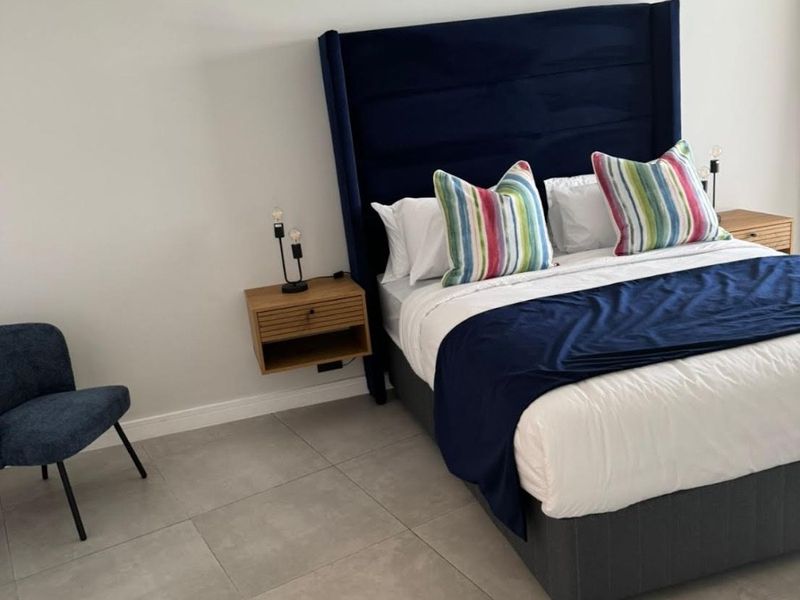 A modern bedroom featuring neutral tiled flooring and wall-mounted floating bedside tables, creating a clean and contemporary aesthetic.