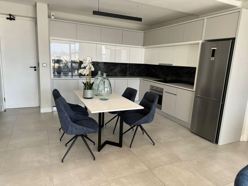 Modern open-plan kitchen featuring sleek handleless cabinetry, stone countertops, a striking black marble splashback, and high-quality integrated appliances in a contemporary penthouse setting.