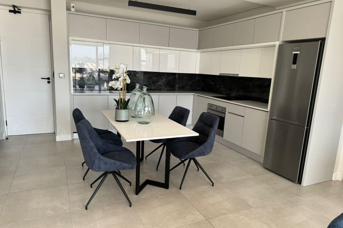 Modern open-plan kitchen featuring sleek handleless cabinetry, stone countertops, a striking black marble splashback, and high-quality integrated appliances in a contemporary penthouse setting.