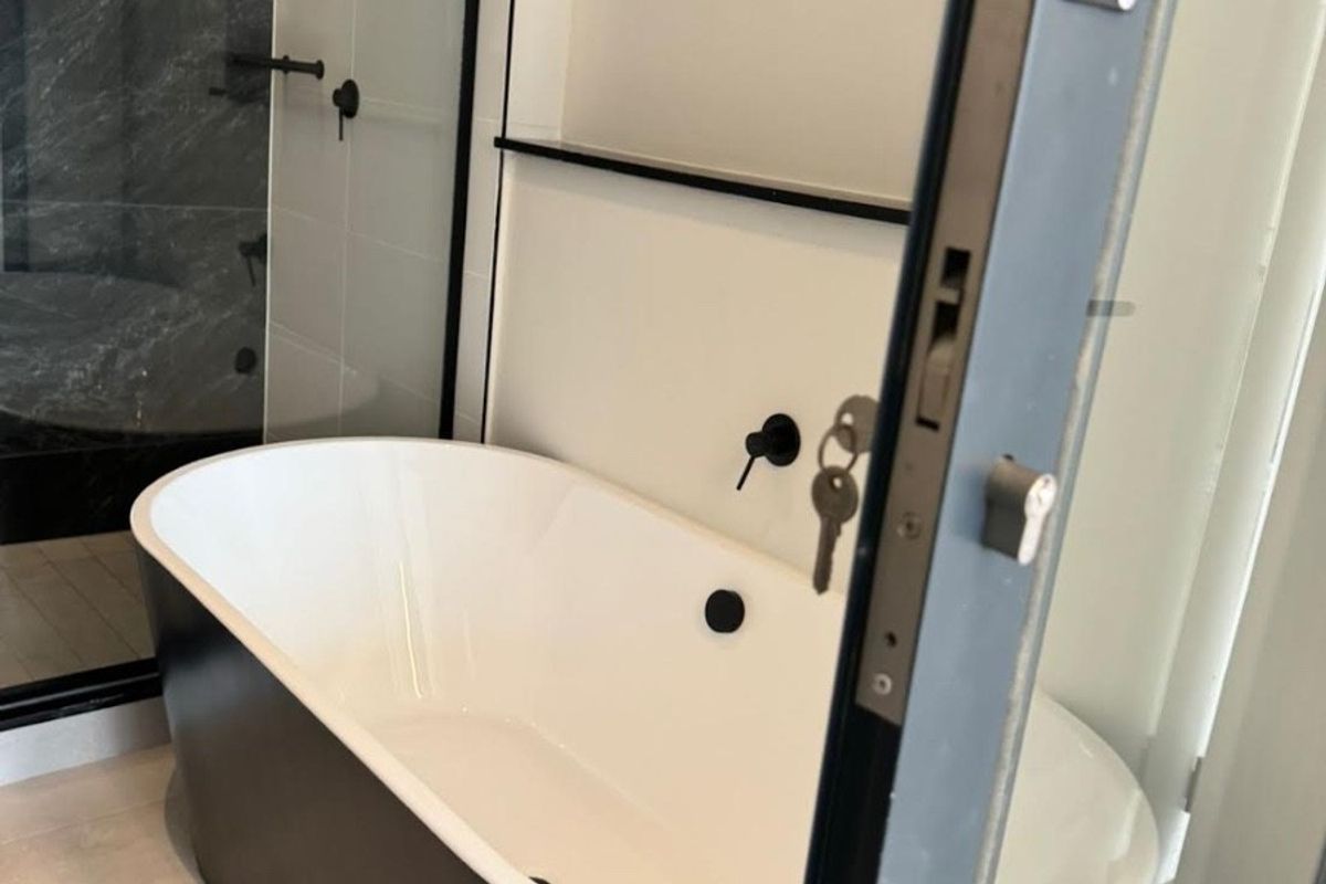 Modern bathroom featuring a sleek freestanding bathtub, walk-in shower with glass screen, and contemporary black matte fixtures.