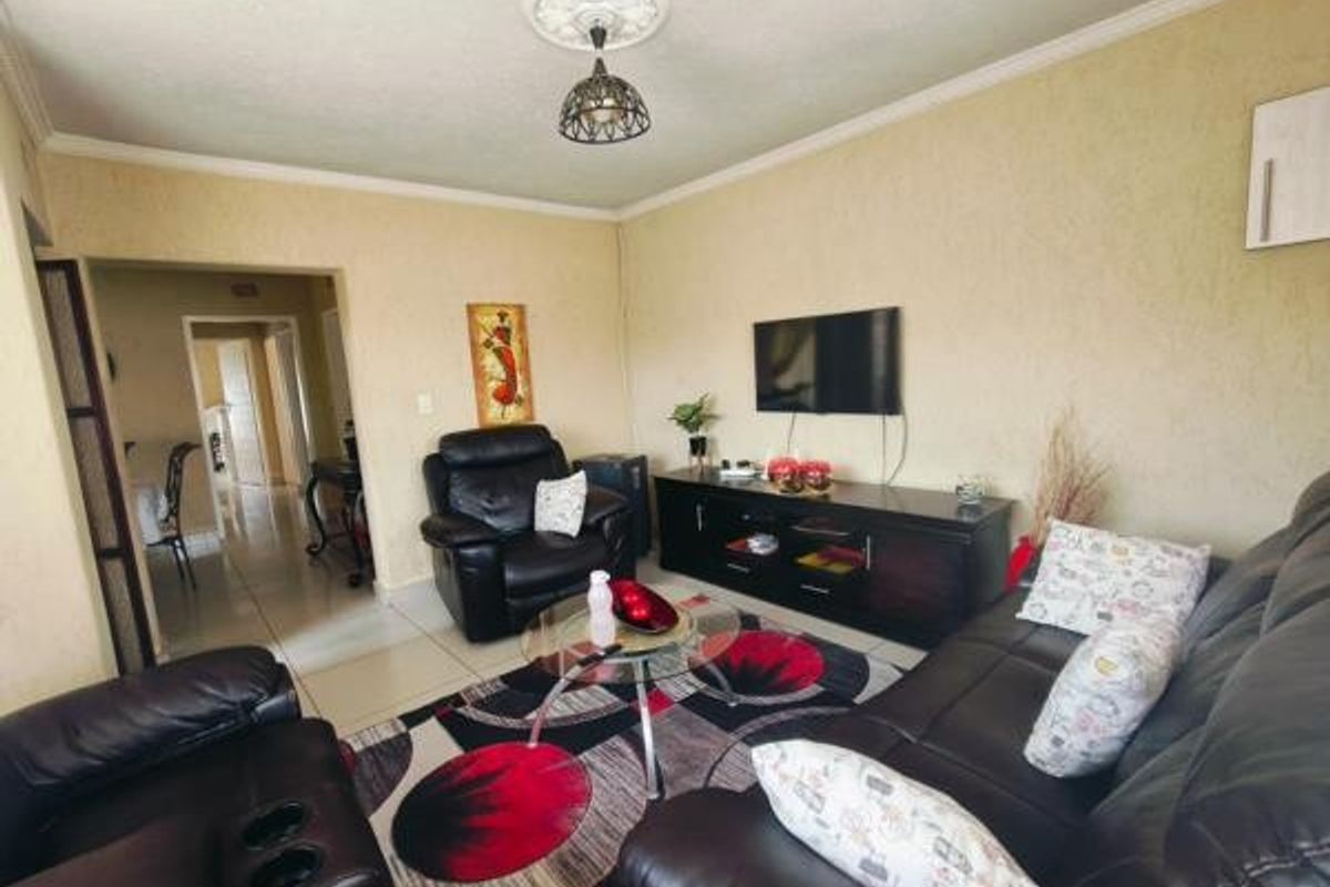 A comfortable living room featuring tiled flooring, decorative ceiling rose, and coving, providing a functional space for relaxation and entertainment.