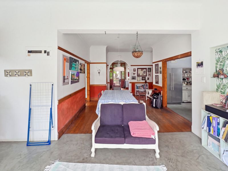 Open plan living and dining area featuring a mix of concrete and timber flooring, traditional archways, and classic timber dado rail detailing.