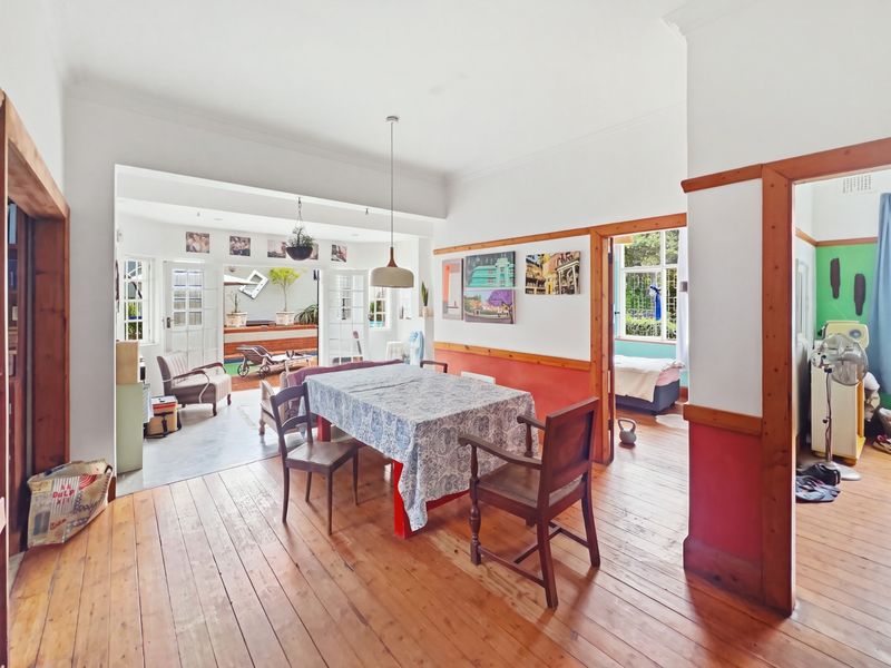 Open plan dining area featuring original timber flooring, decorative wainscoting, and timber door frames, with direct access to an outdoor patio area.