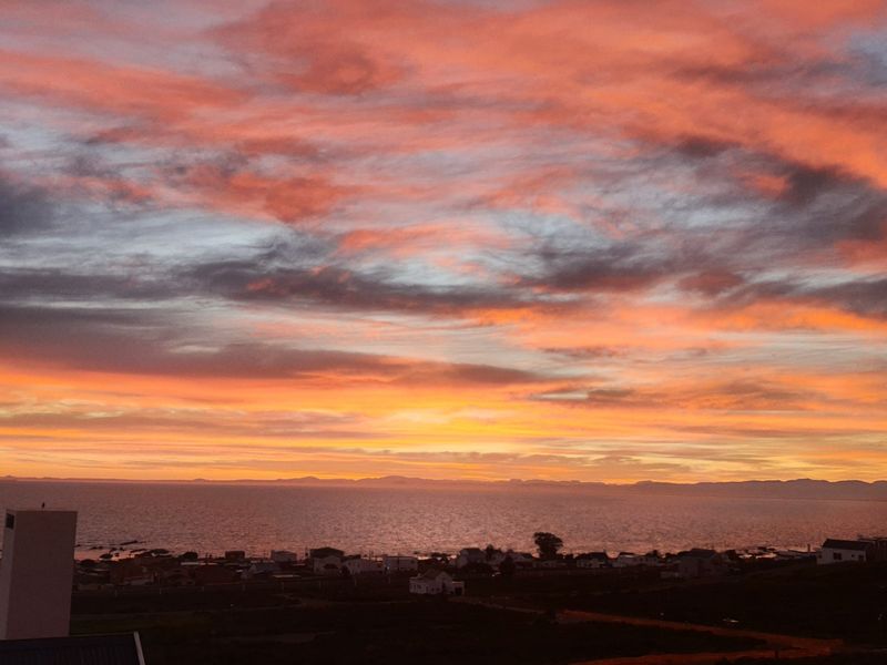 A scenic sunset view overlooking the coastline and residential area, showcasing the property's elevated position and natural surroundings.