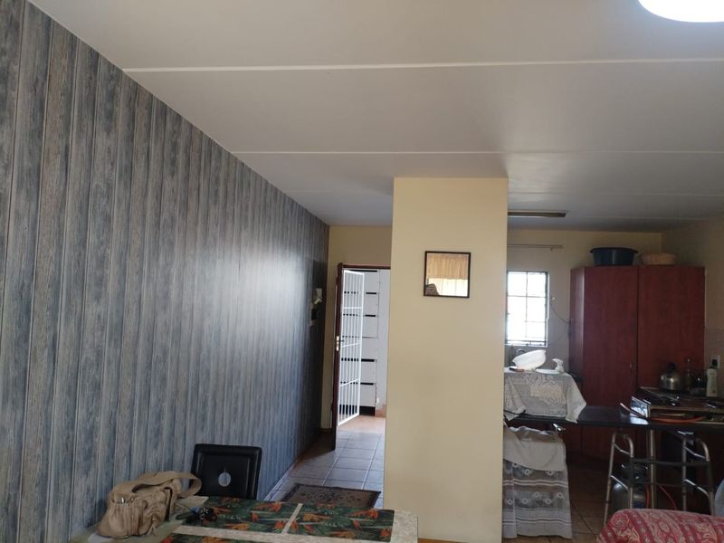 Open plan living area featuring wood-look wall paneling, tiled flooring, and a security gate leading to an adjacent space.